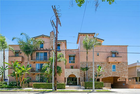 Front view of a multi-story residential building with balconies and a central entryway.