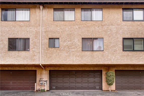 Front view of a multi-story building with three garage doors on the ground level.