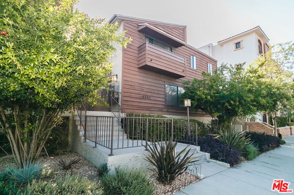 Front view of a multi-story house with a raised entrance and balcony.