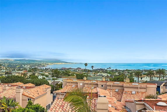 Wide angle view of rooftops with ocean and distant hills in the background.