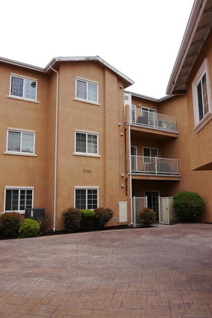 Front view of a multi-story residential building with balconies and multiple windows.