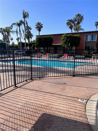 Outdoor swimming pool area with surrounding fence and deck chairs.