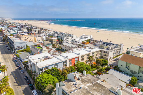 Aerial view of beachfront buildings with a wide sandy beach and ocean in the background.