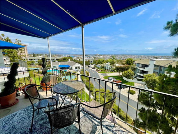Panoramic view from a balcony overlooking residential buildings and a distant coastline.