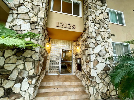 Front view of a building entrance with stone facade and glass door.