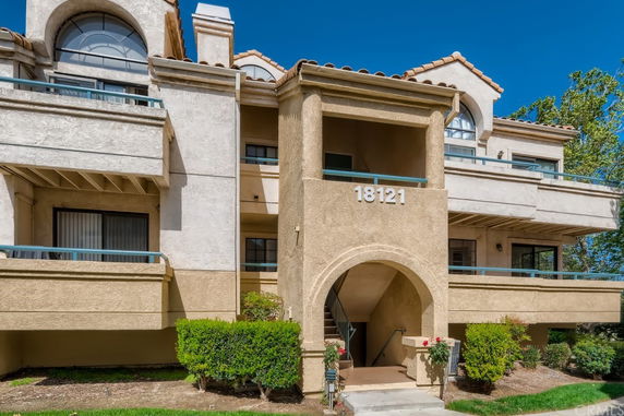 Front view of a residential building with balconies and an arched entrance.