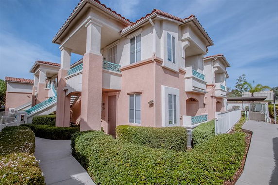 Front view of a two-story residential building with balconies and arched windows.