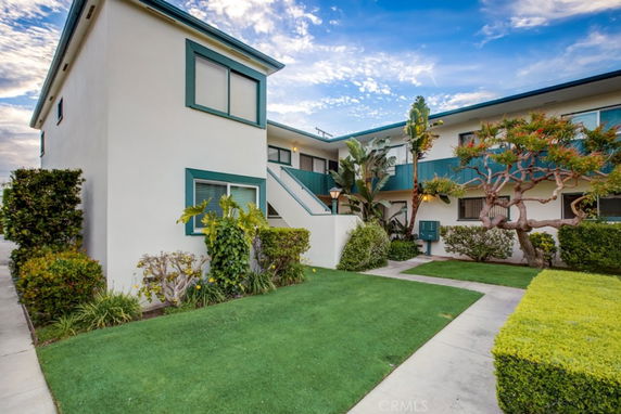 Front view of a multi-story residential building with green trim and landscaped surroundings.