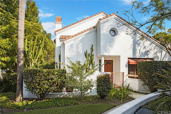 Front view of a white house with a sloped roof and orange tiles.