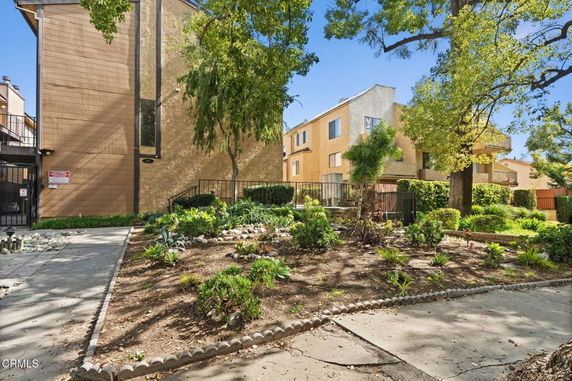 Front view of a multi-story residential building with a landscaped garden area.
