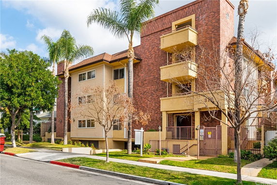 Front view of a multi-story residential building with brick facade and balconies.