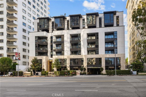 Front view of a modern multi-story apartment building with balconies and large windows.