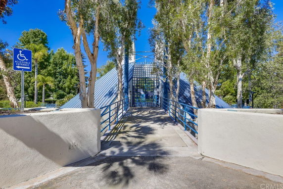 Entrance to a building with a sloped pathway and blue railings.