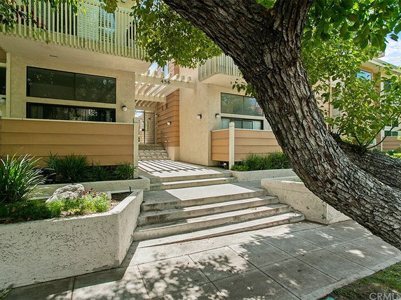 Front view of a multi-story building with stairs leading to an entrance.