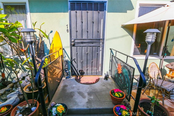 Front entrance of a house with a black door and decorative plants.