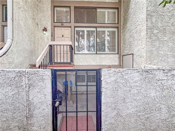 Front view of a residential building entrance with a gated entry and steps leading to the door.