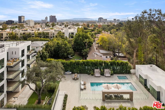 Panoramic view of a modern urban area with a swimming pool and surrounding trees.