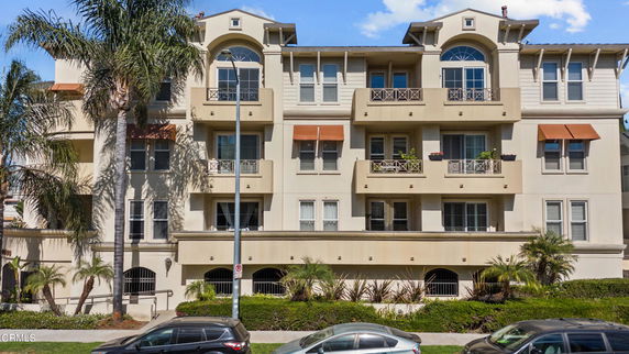 Front view of a multi-story residential building with balconies and arched windows.