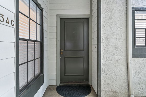 Front view of a residential entrance with a dark door and adjacent windows.