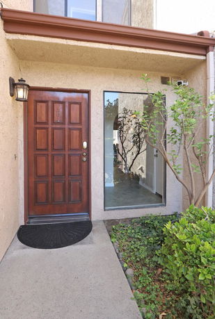 Front view of a house entrance with a wooden door and large window.