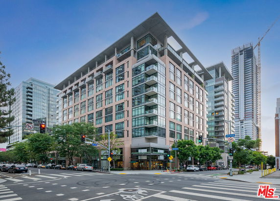 Front view of a modern multi-story building at a street intersection.