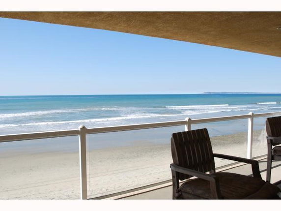 Panoramic view of the ocean from a balcony with chairs.