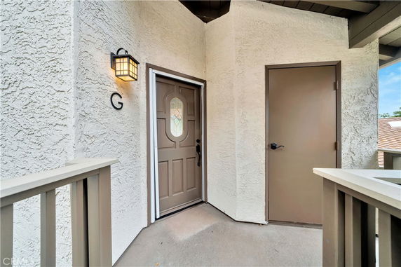 Front view of an apartment entrance with a wooden door and adjacent utility door.
