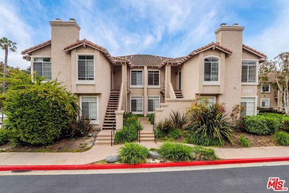 Front view of a two-story residential building with stairs leading to the entrance.