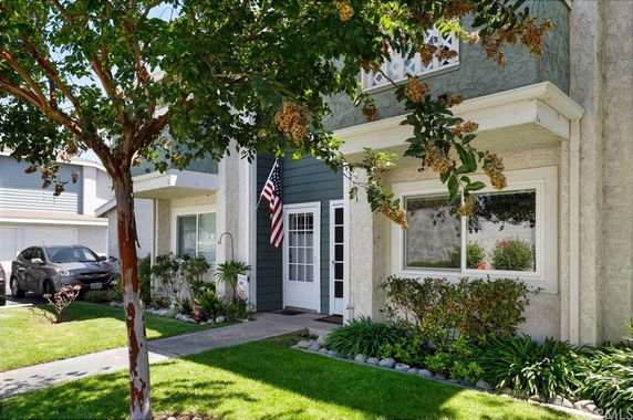 Front view of a two-story house with a small garden and an American flag.