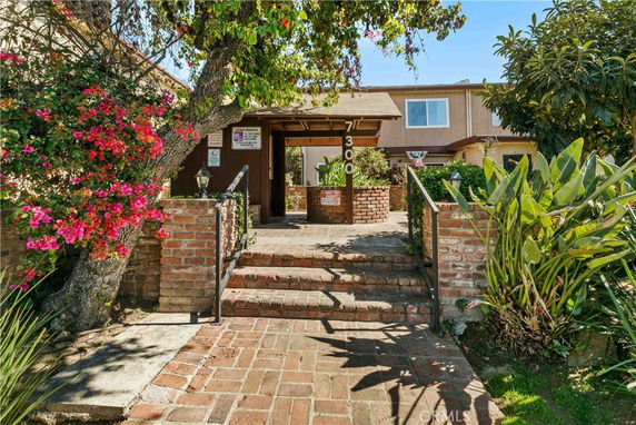 Front view of a house with brick steps and lush greenery.