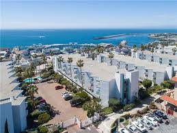 Aerial view of a large residential complex near the ocean with visible parking areas.