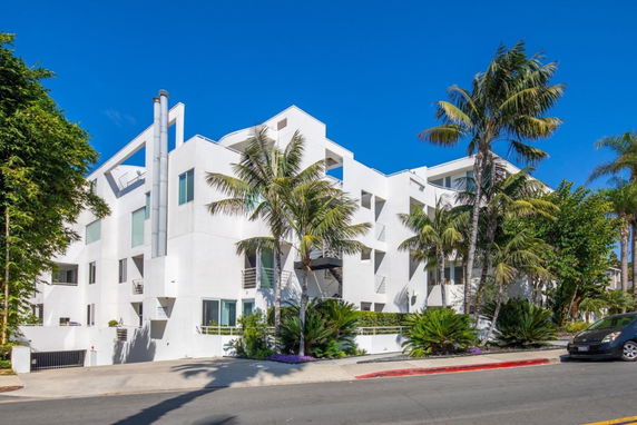 Front view of a modern multi-story building with white exterior and balconies.