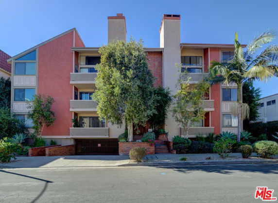 Front view of a multi-story apartment building with multiple balconies and a central entrance.