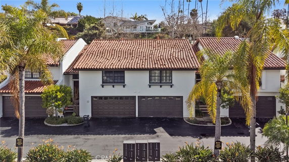 Front view of a multi-story house with garages and red tile roofing.