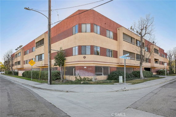 Front view of a three-story apartment building on a street corner.