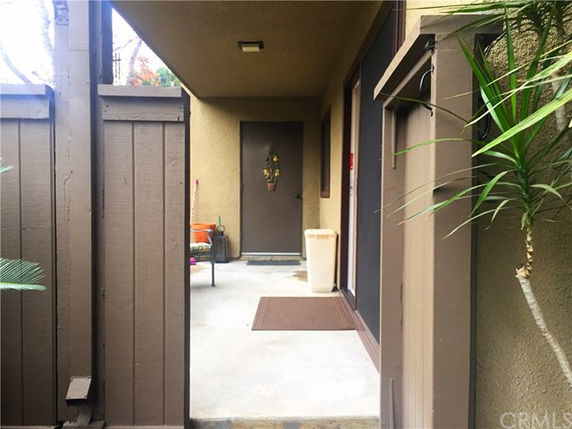 Front view of an entrance to a building with a small porch area and wooden fencing.