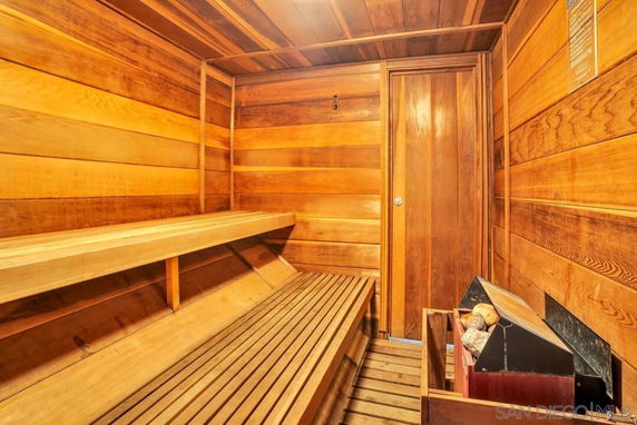 Interior view of a wooden sauna room with benches and a heater.