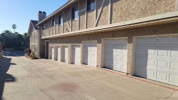 Outdoor parking area with multiple garage doors on a two-story building.