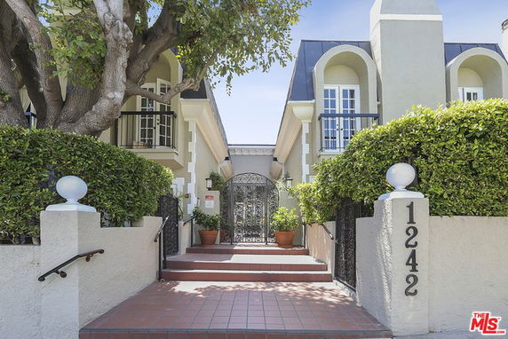 Front view of a multi-story residential building with decorative balconies and a gated entrance.
