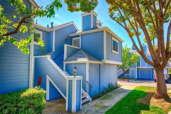 Front view of a blue multi-story house with exterior stairs and a white trim.