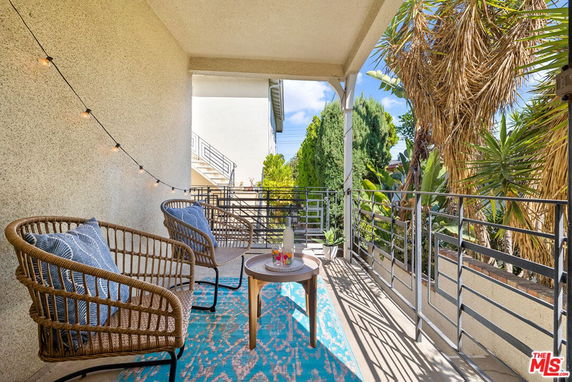 Outdoor balcony with seating and view of landscaped surroundings.
