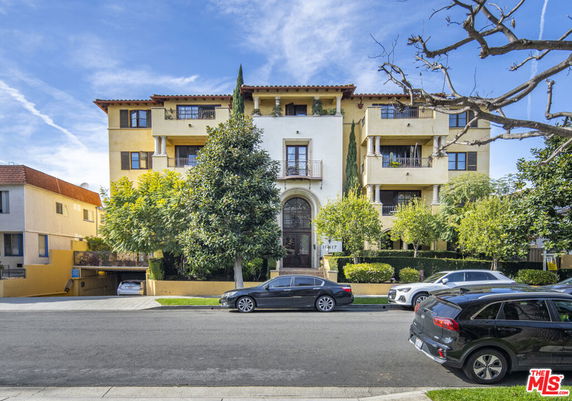 Front view of a multi-story apartment building with balconies and an arched entrance.