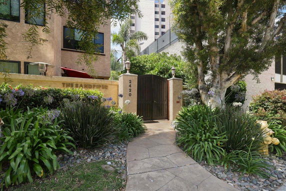 Front view of a building with an entrance gate labeled 'The Sandpiper' and a pathway leading through landscaped gardens.