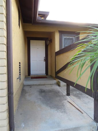 Entrance view of a house with a white door and brown trim.