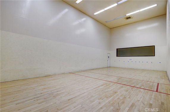 Indoor squash or racquetball court with wooden flooring and high walls.