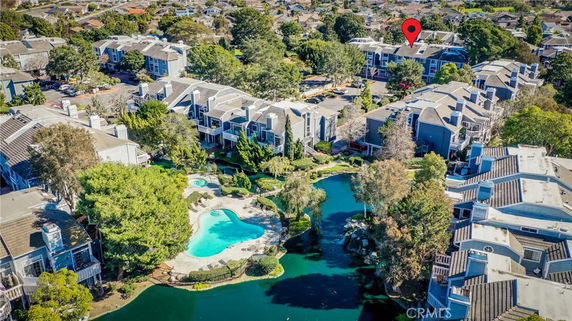 Aerial view of a residential complex with a swimming pool and landscaped gardens surrounded by multiple apartment buildings.