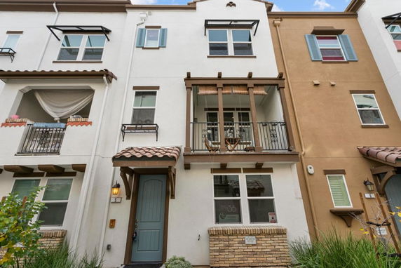 Front view of a three-story townhouse with balconies and a blue front door.