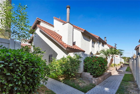 Side view of a two-story house with red-tiled roof and chimney.