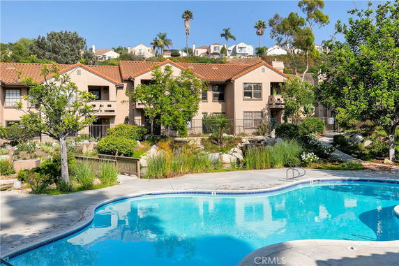 Outdoor area featuring a curved swimming pool with residential buildings in the background.
