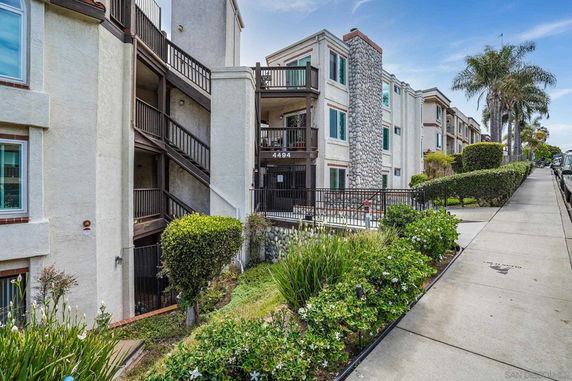 Front view of a multi-story apartment building with an outdoor staircase and stone accents.